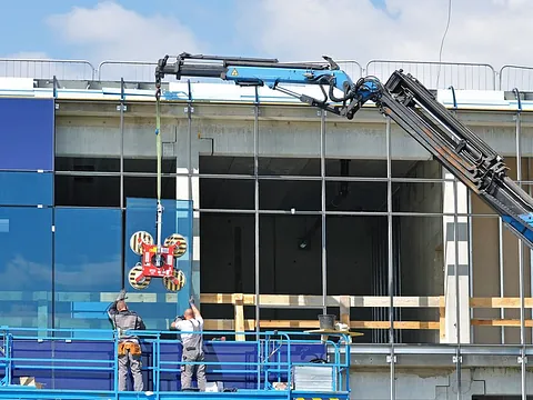 Glaserei Berlin bei der Montage großer Fassadengläser mit Kran und Vakuumsauger auf einer Baustelle.